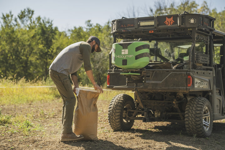 Hooyman 125 lb vehicle spreader broadcasting seed from a UTV