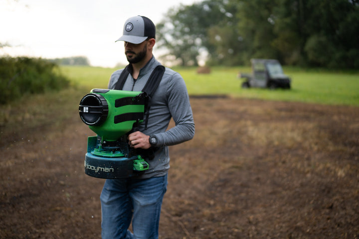 Hooyman 24V chest spreader broadcasting seed on a food plot